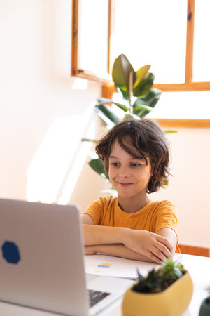 child boy is using a laptop and study online with video call teacher at home, homeschooling, distant...