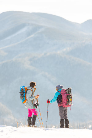two girls stand on top of a mountain. hike in winter.の写真素材
