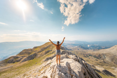 the girl stands against the background of the blue sky. joyful young girl stands on top of the...