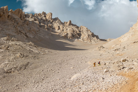 Two tourists with backpacks in the mountains. Tourists travel through the rocky mountains. Active rest in mountain hiking. Adventure in the mountains. group hikesの写真素材