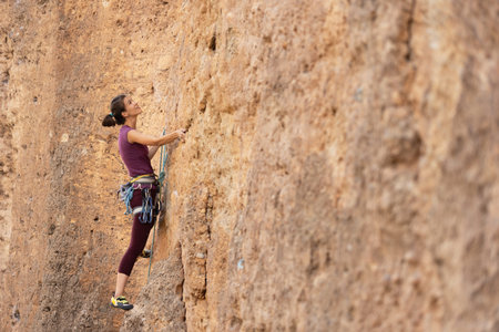 The girl climbs the rock. The climber is training to climb the rock. A strong athlete overcomes a...