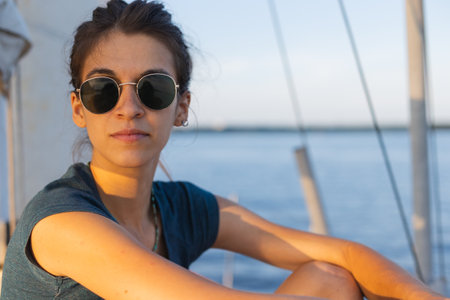 Happy smiling portrait of a beautiful young girl in sunglasses on a yacht or boat on the coast with the sea in the background. paradise island cruiseの写真素材