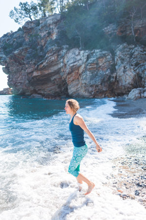 Happy carefree woman walking along the beach. sunny day by the sea. Happy free lifestyle concept. A girl in clothes walks along the seashore.の写真素材