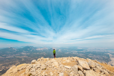 Woman climber with a backpack and a helmet in the mountains. A girl with a backpack walks along a mountain range. adventure and mountaineering concept. hiking with a backpack in the mountains.の写真素材