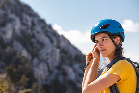 The girl puts on a helmet for mountaineering and climbing. Safety in extreme sports. outdoor sports. adventure and active lifestyle.の写真素材