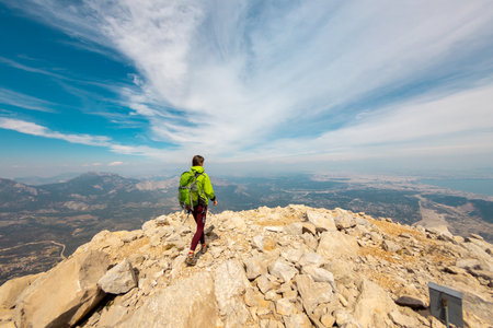 Woman climber with a backpack and a helmet in the mountains. A girl with a backpack walks along a mountain range. adventure and mountaineering concept. hiking with a backpack in the mountains.の写真素材