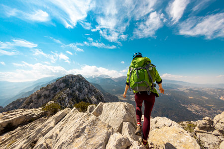 Woman climber with a backpack and a helmet in the mountains. A girl with a backpack walks along a mountain range. adventure and mountaineering concept. hiking with a backpack in the mountains.の写真素材