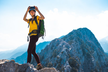 climber on top of the mountain takes a photo. Woman traveler takes a photo on a modern smartphone, makes beautiful pictures of beautiful mountain landscapes. mountain climbing and adventure.の写真素材