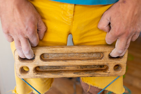 strong male hand of a rock climber holds a board for training finger strength. climbing workout at home. rock climber's hand close-up. strength and endurance. fingerboard and hangboardの写真素材
