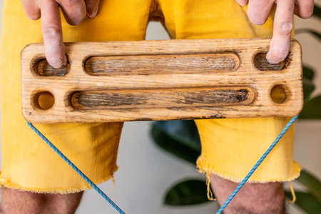 strong male rock climber's hand holds board for finger strength training with one finger. climbing workout at home. rock climber's hand close-up. fingerboard and hangboardの写真素材