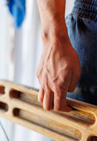 strong male hand of a rock climber holds a board for training finger strength. climbing workout....