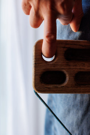 strong male rock climber's hand holds board for finger strength training with one finger. climbing workout at home. rock climber's hand close-up. fingerboard and hangboardの写真素材