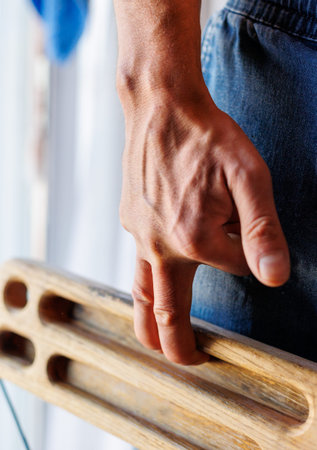 strong male hand of a rock climber holds a board for training finger strength. climbing workout at...
