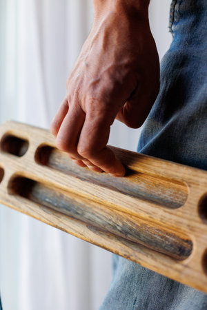 strong male hand of a rock climber holds a board for training finger strength. climbing workout. rock climber's hand close-up. strength and endurance. fingerboard and hangboard. extreme sportsの写真素材