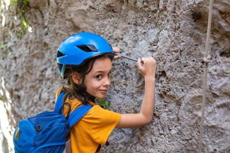boy in a helmet and with a backpack in the mountains. the child is on vacation. the boy climbs stones.の写真素材