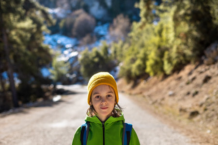 Portrait of a boy with a backpack in the forest. The child is standing in the middle of the road in the forest. hiking and travel.の写真素材