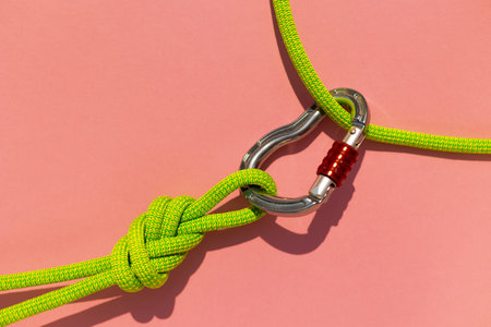 carabiner with a rope lies on a colored background. Equipment for climbing and mountaineering....