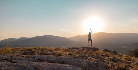 silhouette of a jumping man against the background of the sky and sunset in the mountains, sports and recreation.の写真素材