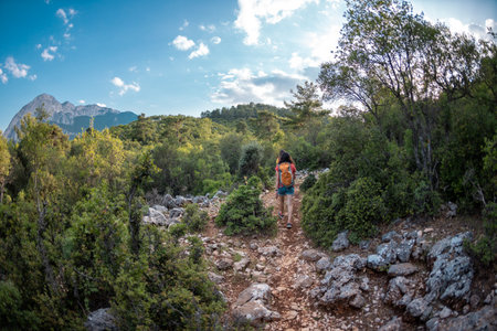 Two girls with a backpack walk along a mountain road, women against the backdrop of a beautiful mountain and sky, a journey through the beautiful places of the world, travel to Turkeyの写真素材