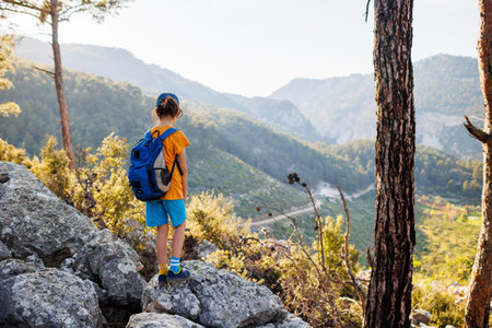 Travel child. a tourist with a backpack stands on a mountain path looks at the mountains. hiking and active healthy lifestyle. adventure holidays with children.の写真素材