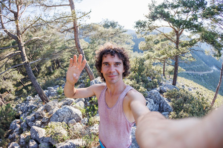 Happy male tourist takes a selfie in the forest. A man takes a selfie on the street. An influential travel blogger enjoys a trip while taking a self-portrait. Summer holidays and weekend activities.の写真素材