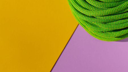green rope for rock climbing and mountaineering lies on a colored background. background image of...