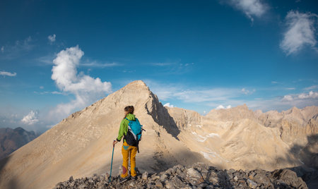 Hiking in the mountains. A girl with a backpack walks along a mountain path. Adventure climbing in the mountains. freedom and adventure concept.の写真素材