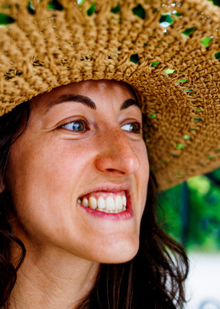 portrait of a young happy brunette in a straw hat. The girl smiles and enjoys her vacation...