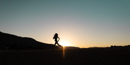 girl runs at sunset in the mountains. skyrunning. a young girl runs along a mountain range at...