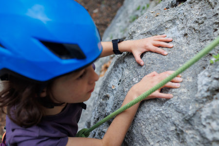 boy rock climber in a blue protective helmet overcomes the route in the mountains. children's sports in nature. active time in nature.の写真素材