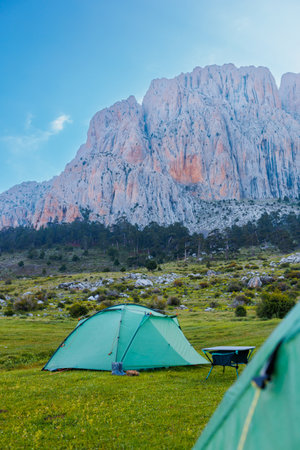 Green camping tents stand on a green meadow with beautiful mountains in the background. Spending time outdoors. Travel and camping concept. Dedegol. Turkey.の写真素材