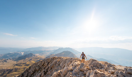 a girl walks along the ridge of a mountain against the background of the sky and mountains. mountain run. travel and adventure.の写真素材