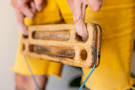 strong male rock climber's hand holds board for finger strength training with one finger. climbing workout at home. rock climber's hand close-up. fingerboard and hangboardの写真素材