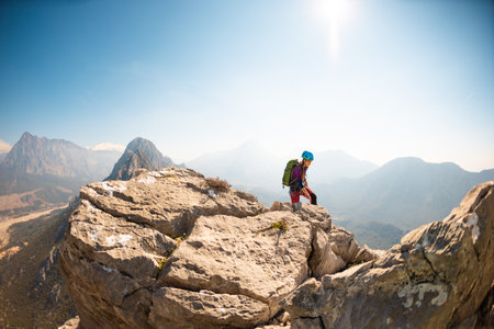 hiking in the mountains. a girl with a backpack walks along a mountain range. climbing and hiking in the mountains.の写真素材