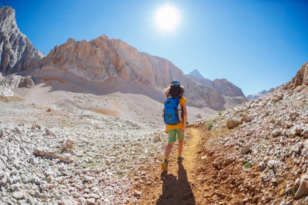 child travel in the mountains with a backpack. mountain hike in high mountains. the boy is walking along a mountain path. Turkey.の写真素材
