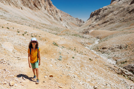 child travel in the mountains with a backpack. mountain hike in high mountains. the boy is walking along a mountain path. Turkey.の写真素材