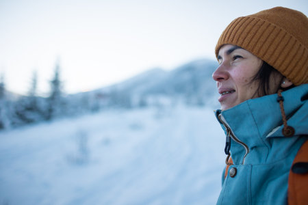 woman with a backpack in a winter hike, winter trekking, a girl on the background of snow-capped mountainsの写真素材