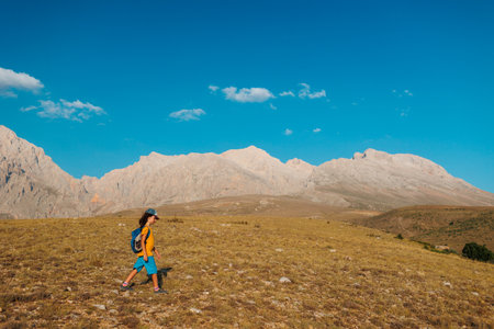 a little boy with a backpack walks along a path against the backdrop of mountains. travel and hikes. travel with children to the mountains. Turkey. Aladaglar.の写真素材