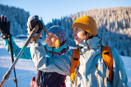 Two women walk in the snow, winter trekking, two people in the mountains in winter, hiking equipment
