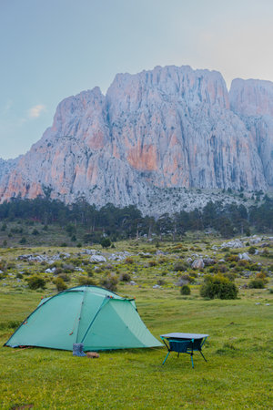 A green camping tent stands on a green meadow with beautiful mountains in the background. Spending time outdoors. Travel and camping concept. Dedegol. Turkey.の写真素材