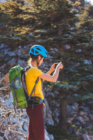 climber on top of the mountain takes a photo. Woman traveler takes a photo on a modern smartphone, makes beautiful pictures of beautiful mountain landscapes. mountain climbing and adventure.の写真素材