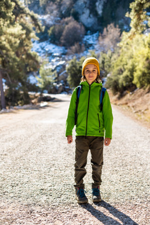boy with a backpack in the forest. The child is standing in the middle of the road in the forest. hiking and travel.の写真素材