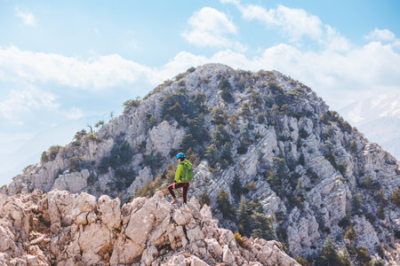 climber with a backpack and a helmet goes along a mountain path in the mountains. Girl climber in the mountains. adventure and mountaineering concept. hiking with a backpack in the mountains.の写真素材