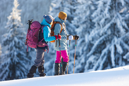 Two women walk through the snow on a winter hike, two women in the mountains in winter, hiking equipment, snowshoesの写真素材