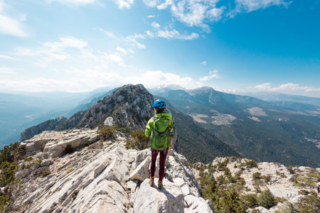 climber stands on top of the mountain. girl climber in a helmet and with a backpack mountains. the concept of adventure and hiking in the mountains. Turkey.の写真素材