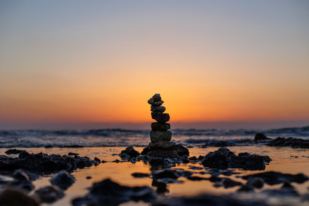 Stone balance on the beach at sunset. Pyramid of the small pebbles on the beach. Stones, against the background of the sea shore during sunset.の写真素材