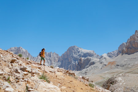 child travel in the mountains with a backpack. mountain hike in high mountains. the boy is walking along a mountain path. Turkey.の写真素材