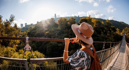young girl in a hat stands on a suspension bridge and looks dreamily into the distance. close-upの写真素材