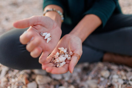 rest and meditation. a girl sits on the beach and pours shells in her hands. girl's hands with...