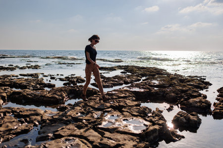 girl walks along a rocky beach. walk along the sea. girl enjoying a walk by the sea.の写真素材